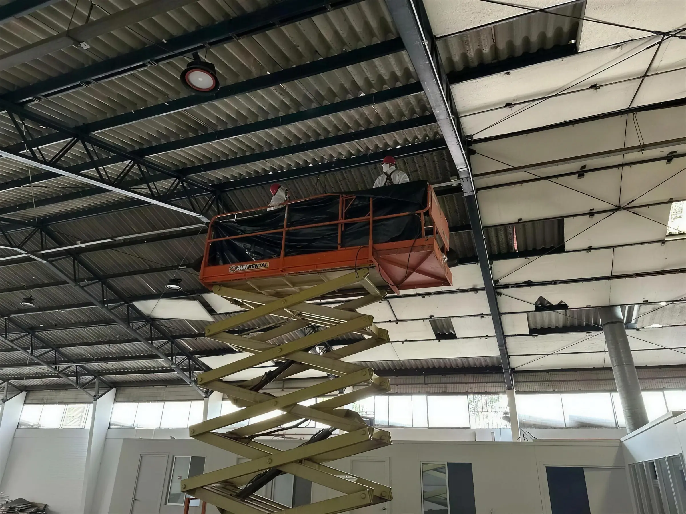 Alza hombre trabajando bajo la cubierta de un galpón